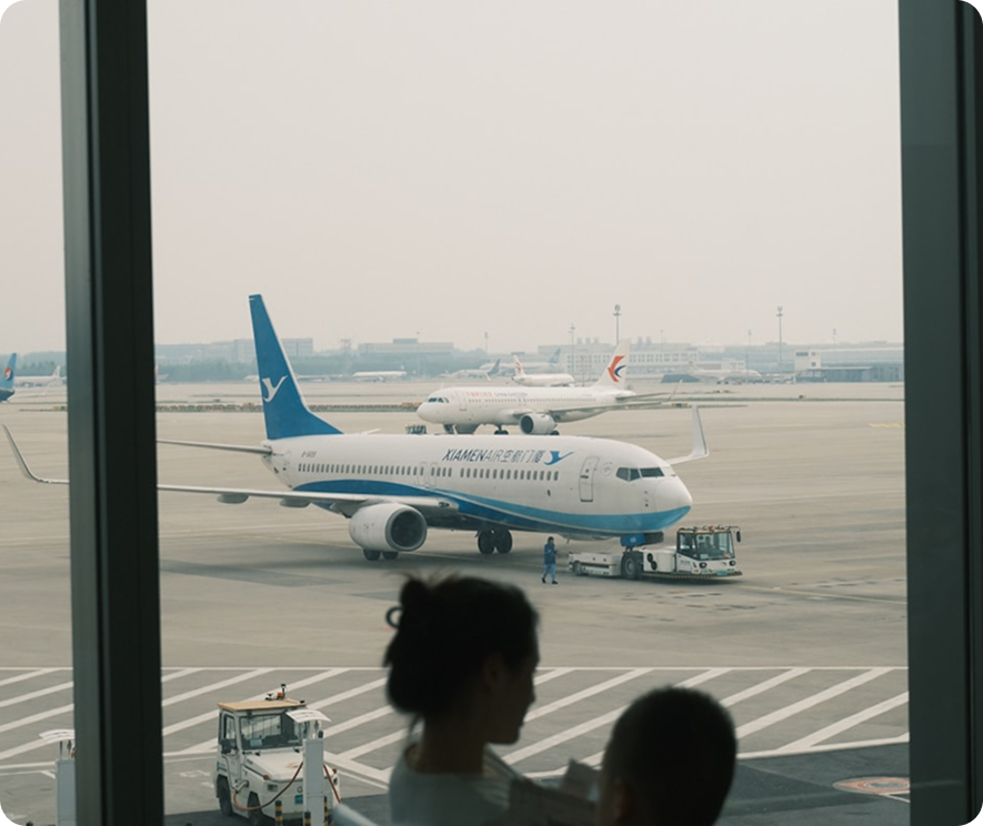 a picture of two people's silhouette on a window showing an airplane in an airport