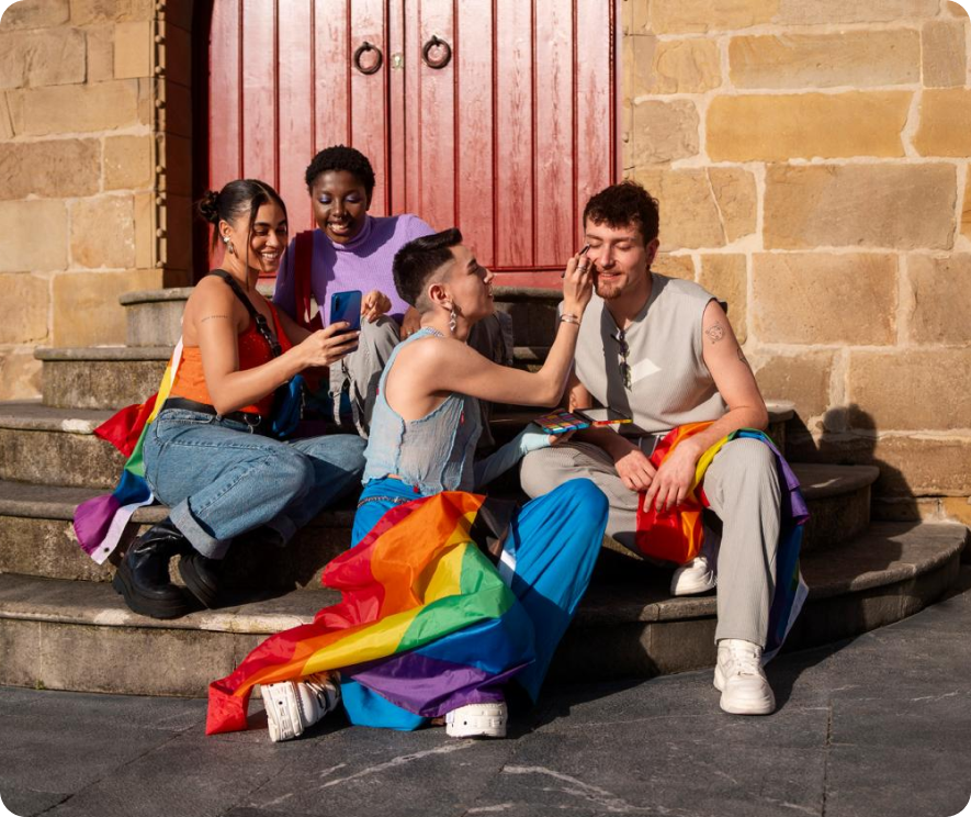 Un grupo de amigos en unas escaleras, con parafernalia del orgullo